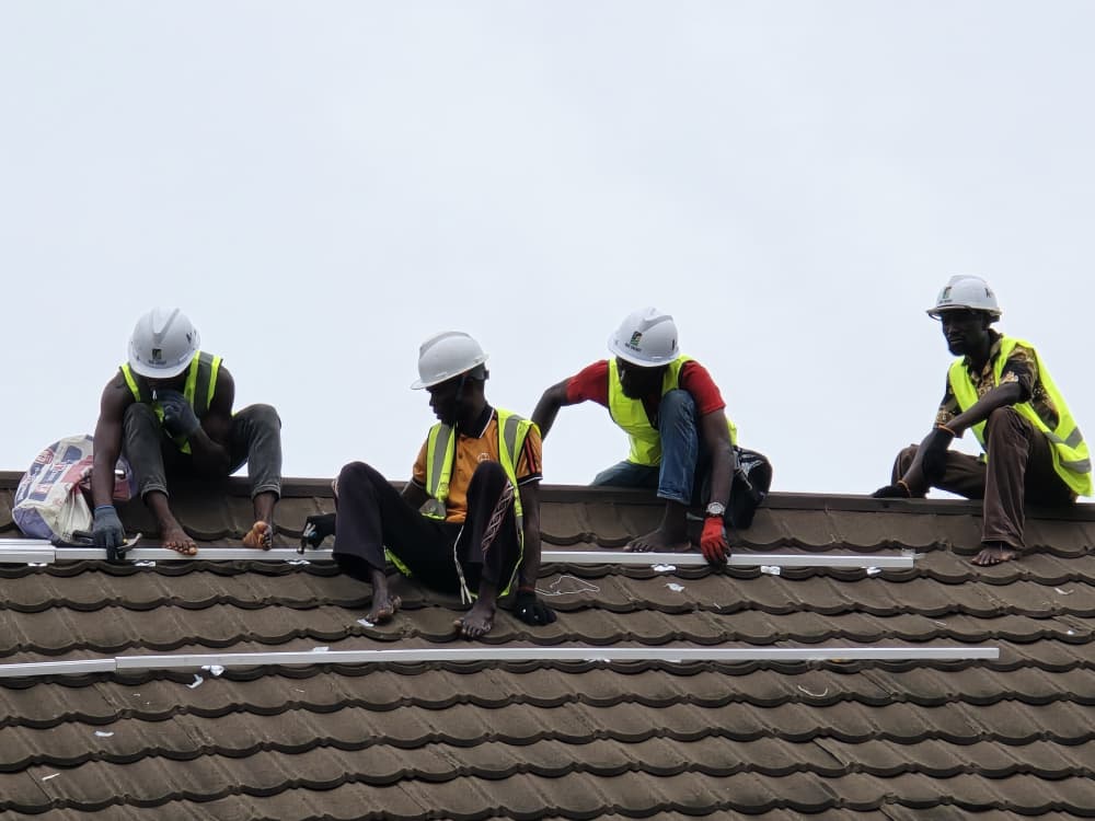 Technicians in safety gear fitting mounting rails on a roof